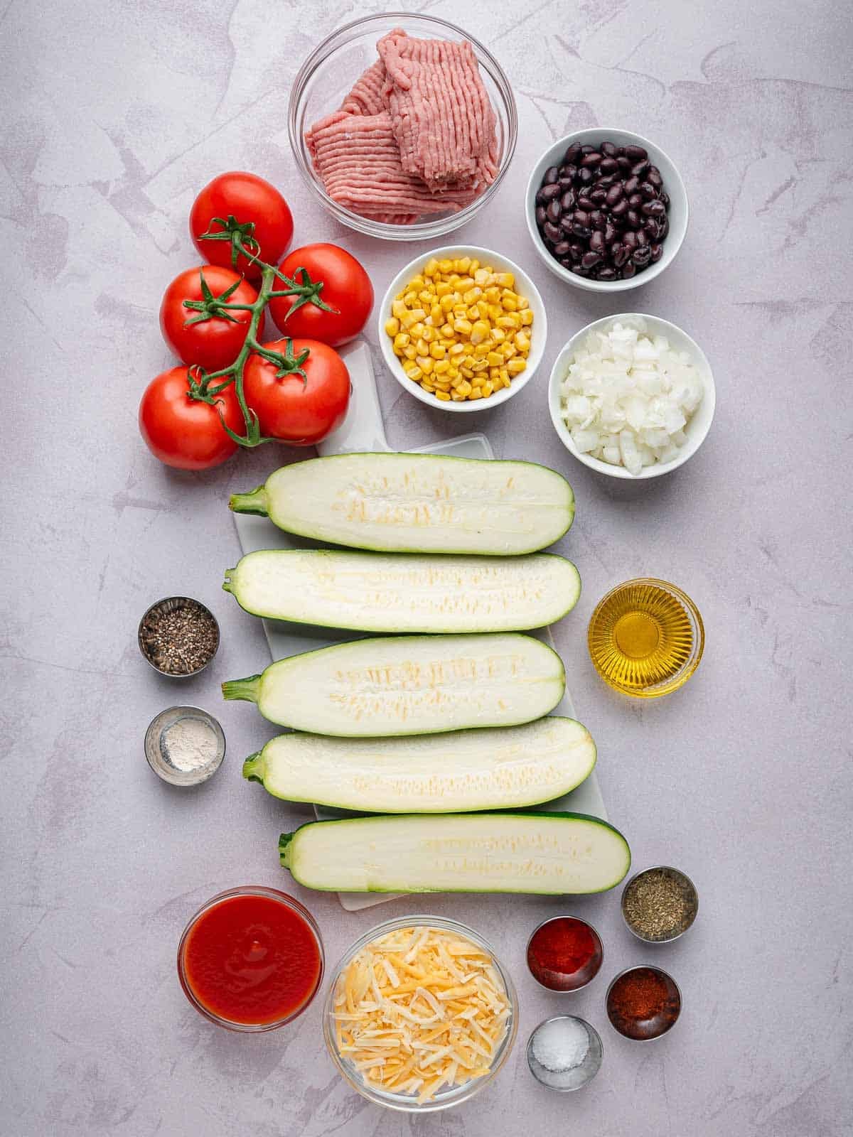 Ingredients for stuffed zucchini boats with ground turkey, black beans, corn, tomatoes, and cheese.