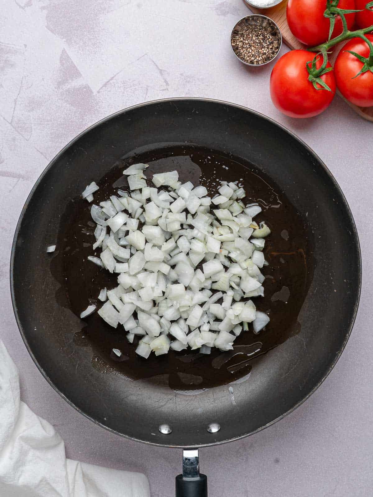 Diced onion cooking with olive oil in a skillet.
