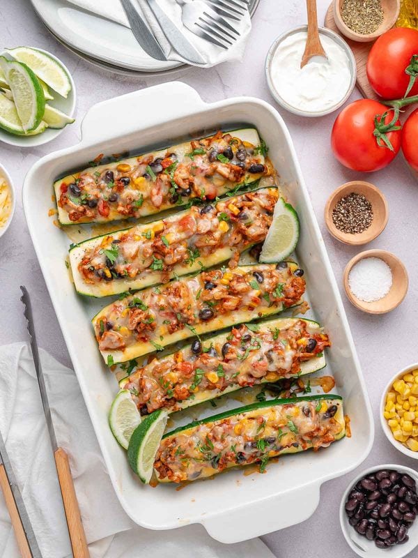 Southwest stuffed zucchini boats with melted cheese, cilantro, and lime wedges.