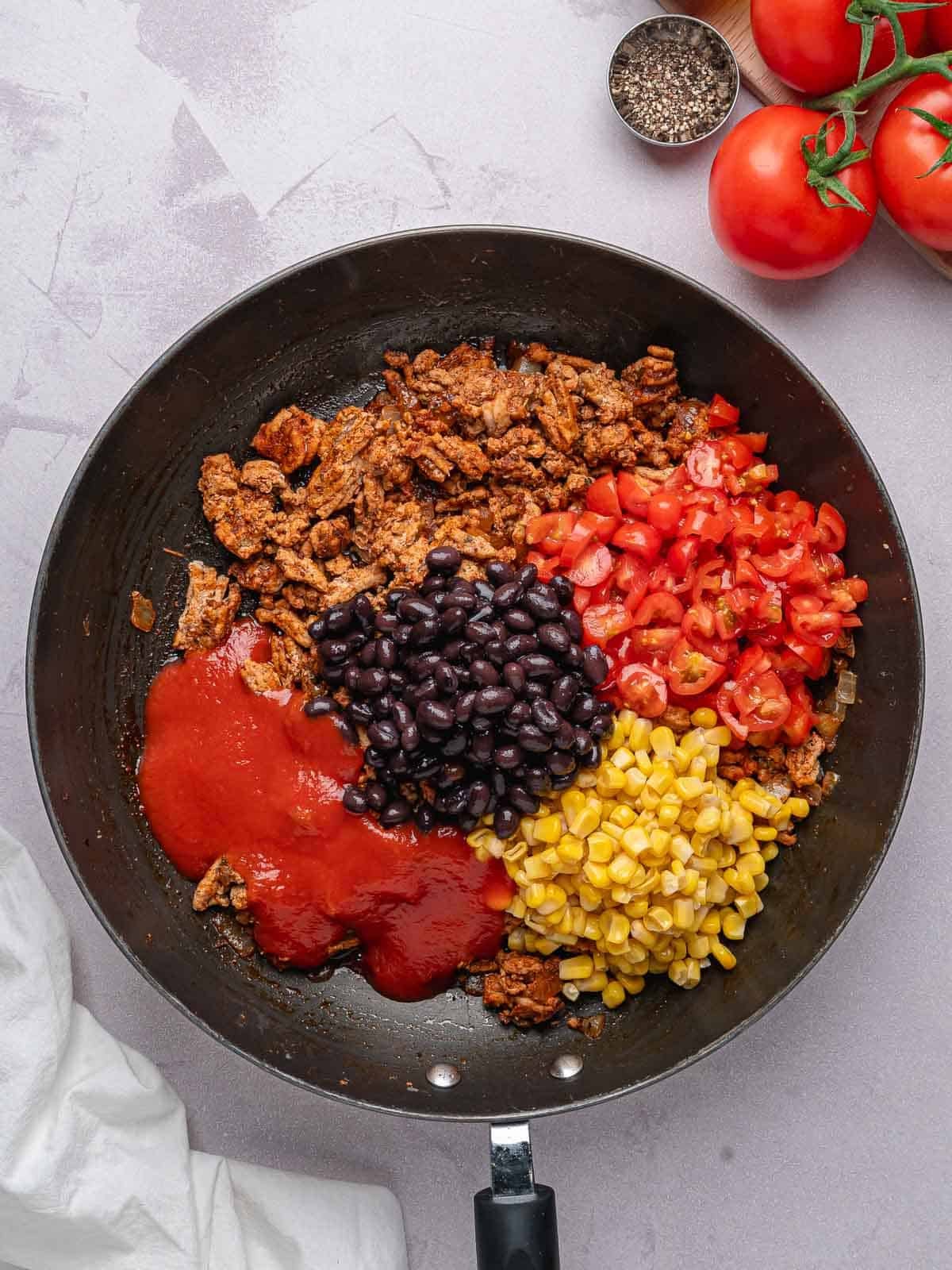 Ground turkey with black beans, corn, tomatoes, and tomato sauce added to the skillet.