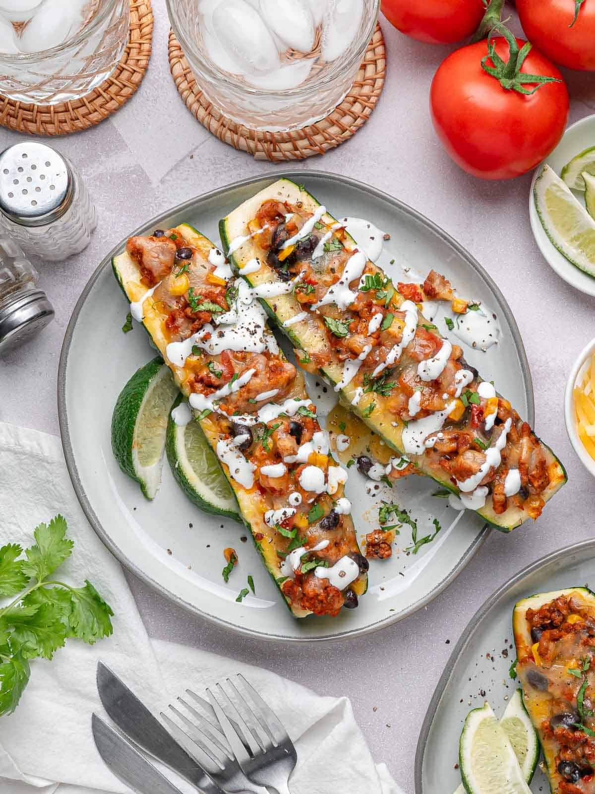 Stuffed zucchini boats served with sour cream, cilantro, and lime wedges.