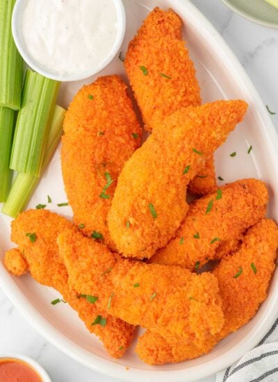 A plate of buffalo chicken fingers with celery and dip.