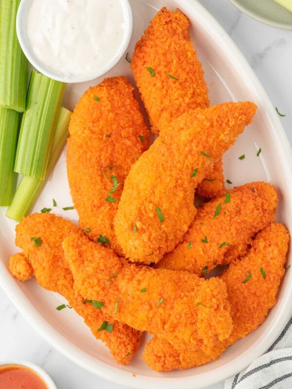 A plate of buffalo chicken fingers with celery and dip.