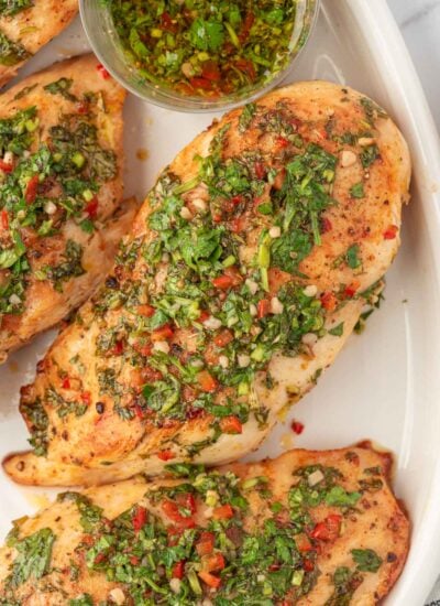 Baked chicken with chimichurri sauce on a plate.