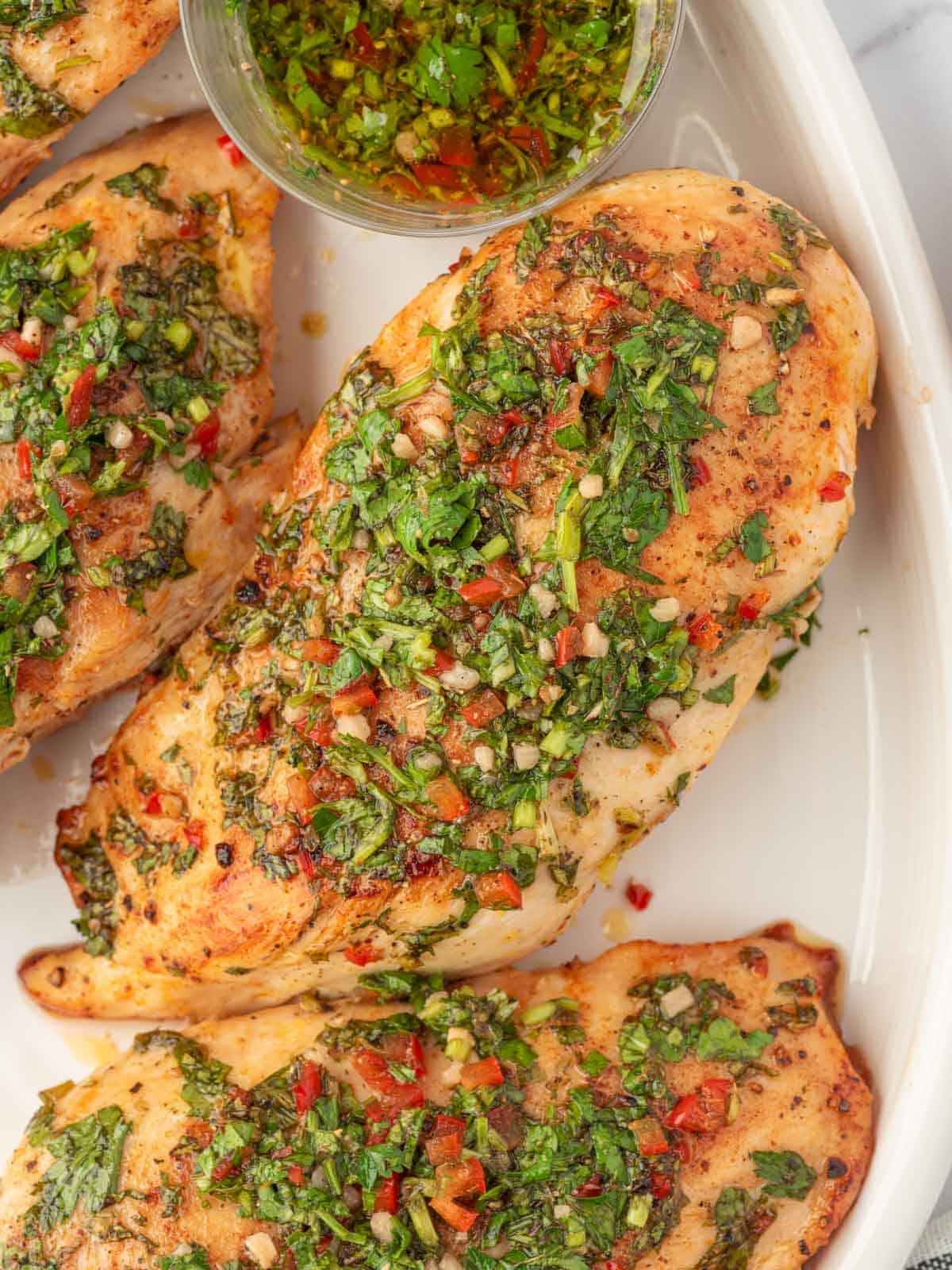 Baked chicken with chimichurri sauce on a plate.