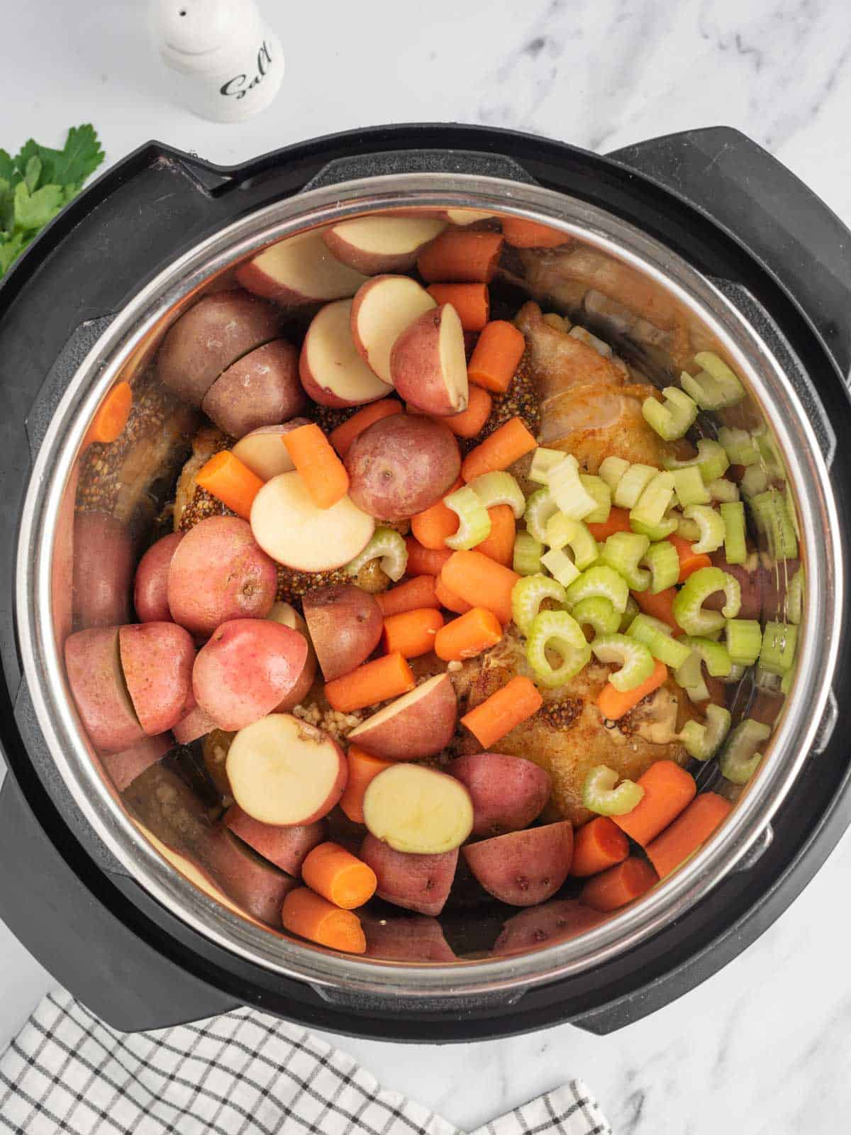 Add potatoes and carrots to the instant pot with chicken thighs.