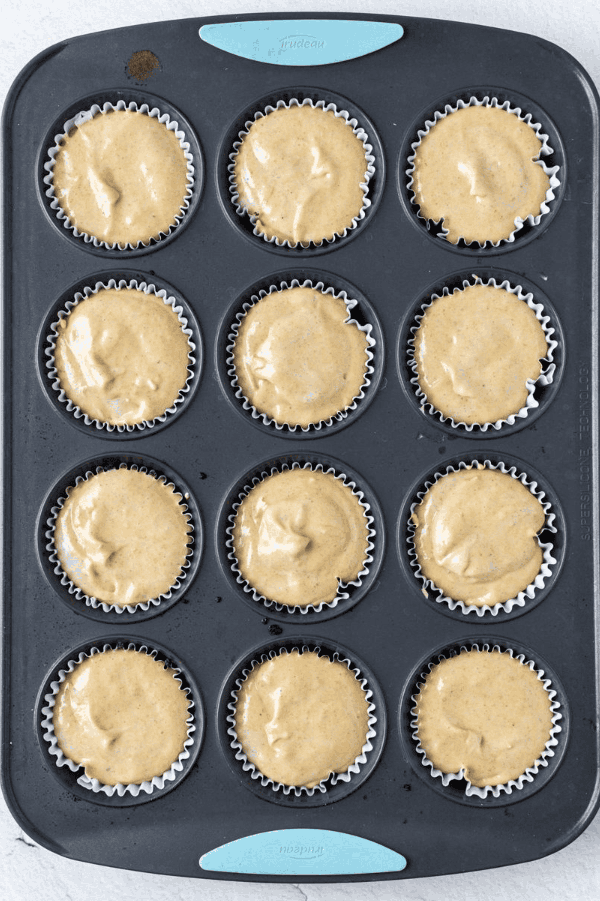 Pumpkin cheesecake filling divided among pre-baked Oreo crusts in cupcake liners.