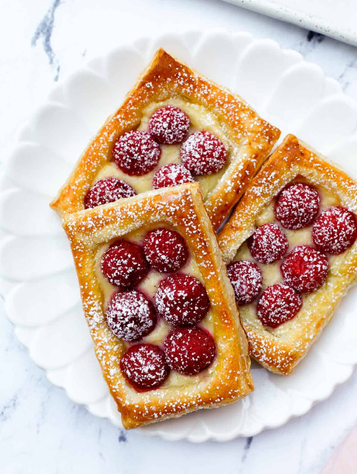 raspberry tart baked on a plate, dusted with powdered sugar