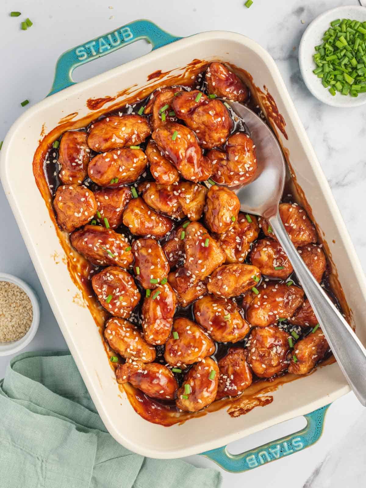 A casserole dish of asian chicken breast with sesame seeds.