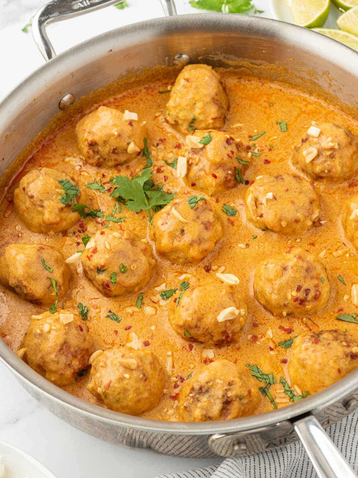Chicken meatballs with curry sauce in a skillet.