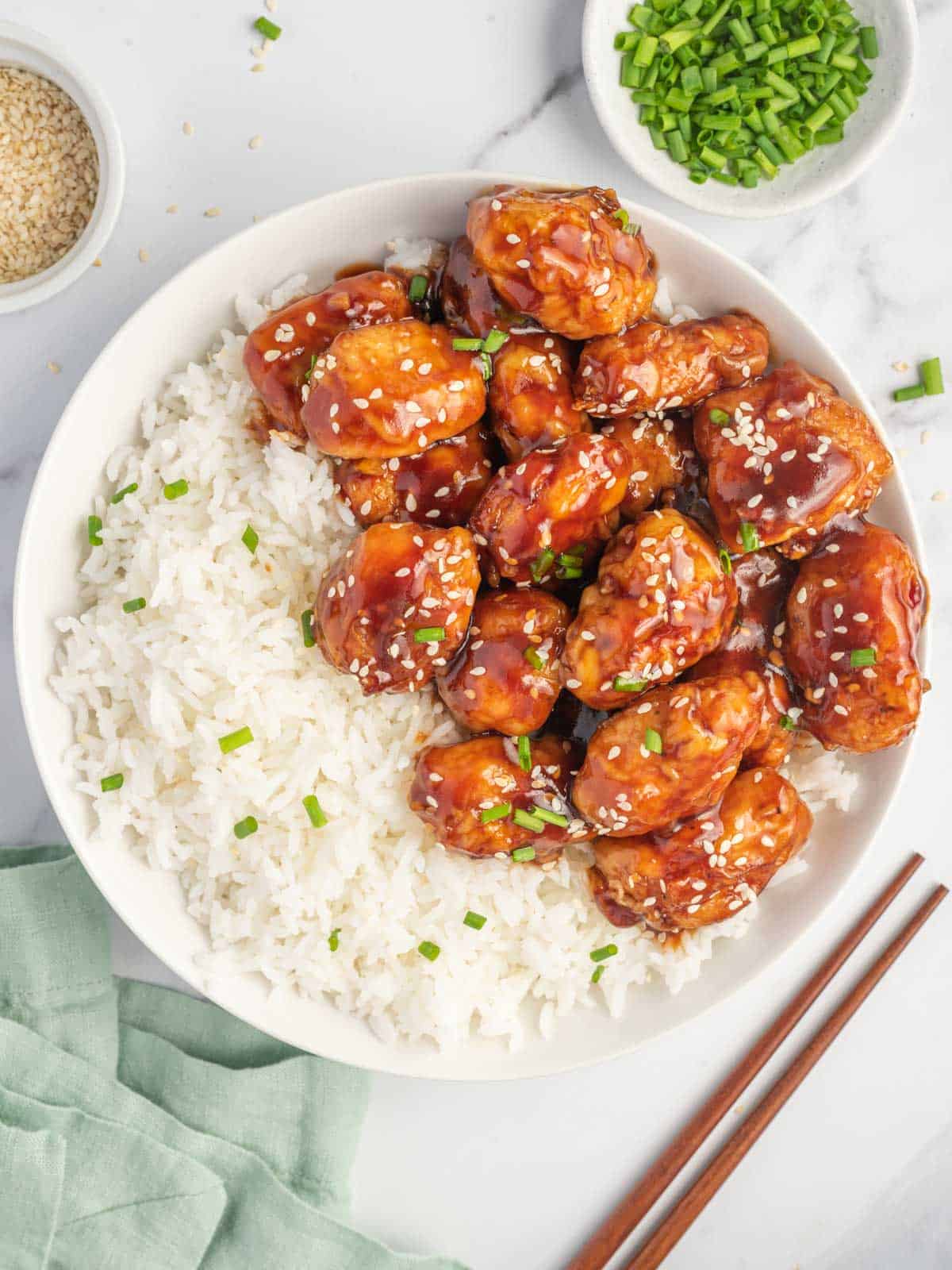 Baked honey sesame chicken on a plate with rice.