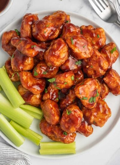 Top view of bbq chicken nuggets with celery on a plate.