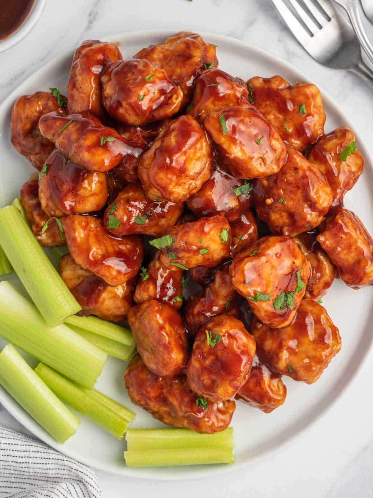 Top view of bbq chicken nuggets with celery on a plate.