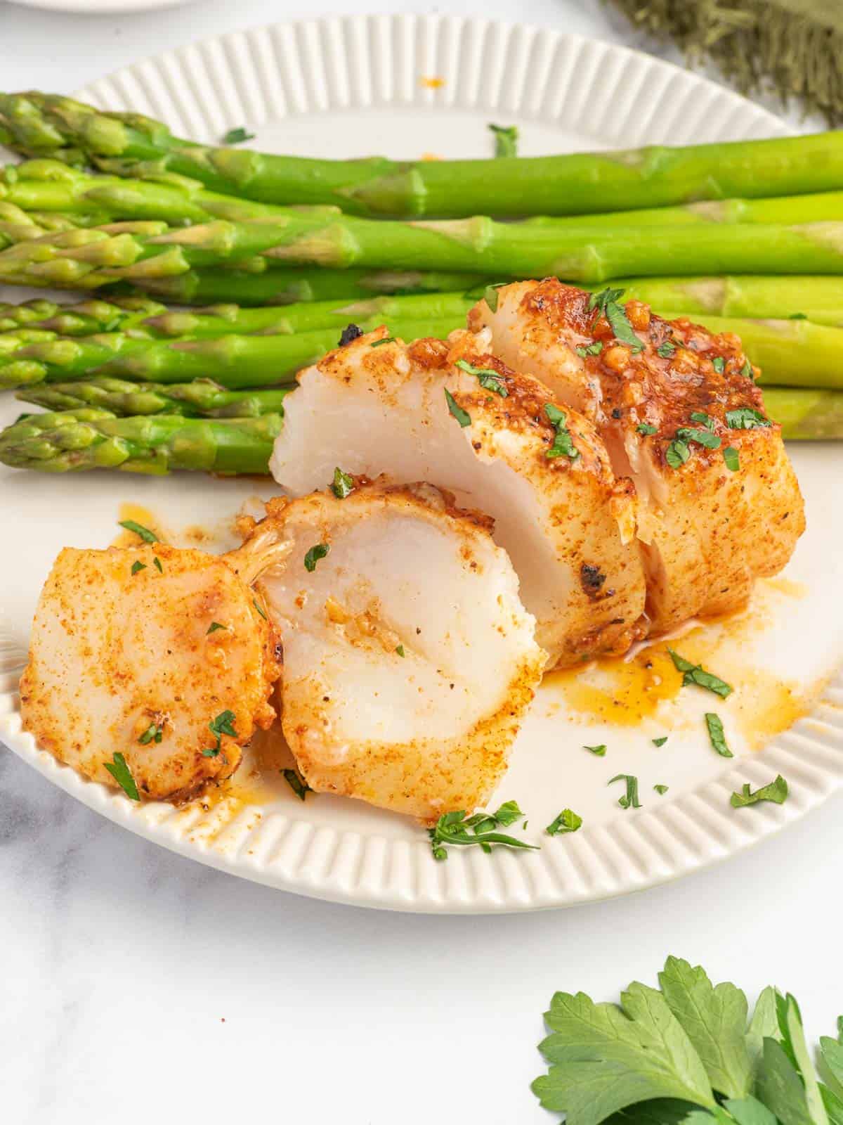 Flaked cod filets on a plate with asparagus.