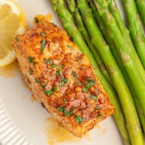 A filet of cajun cod on a plate with asparagus.