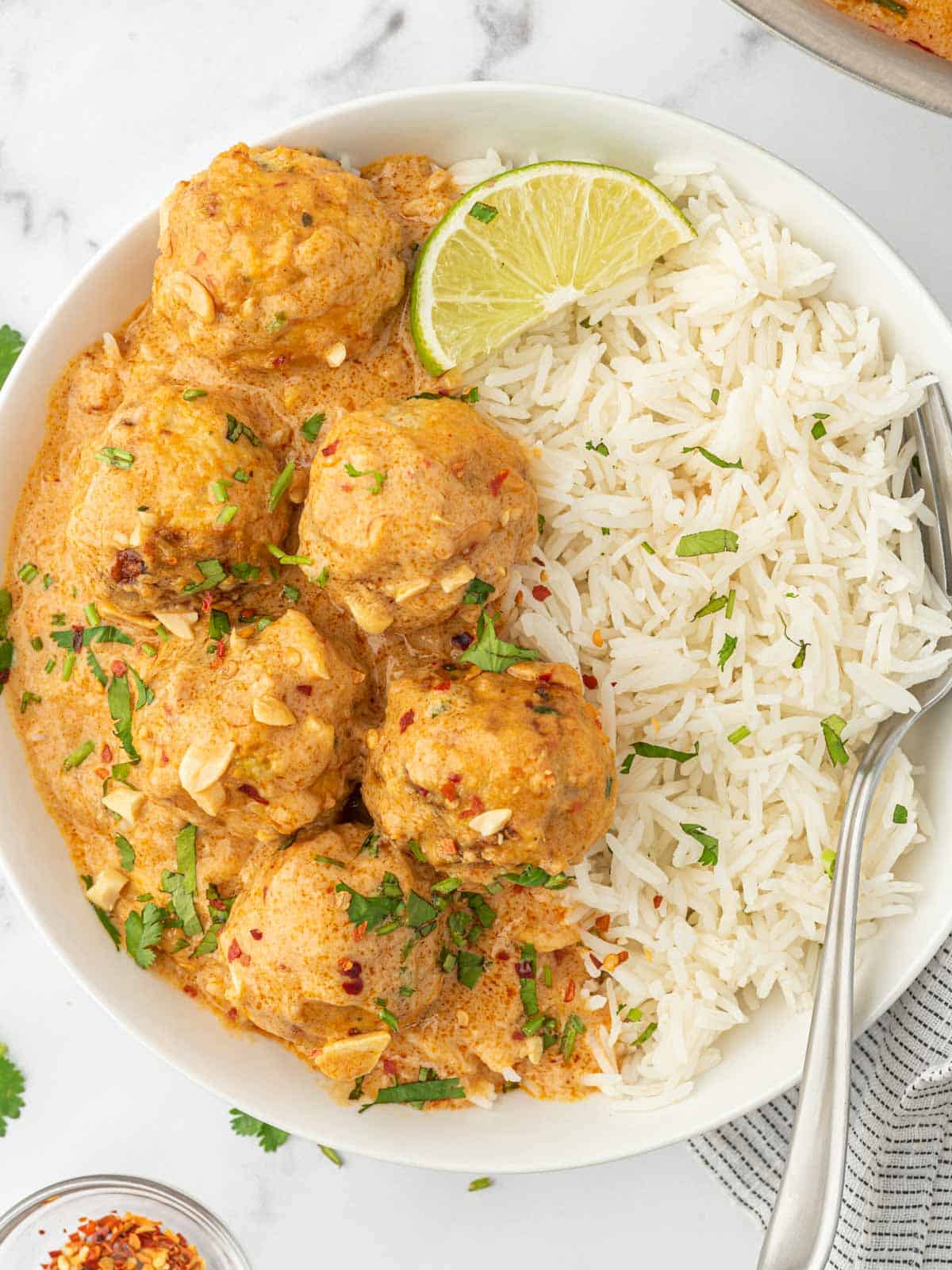 Thai chicken meatballs and rice in a white bowl with a fork.