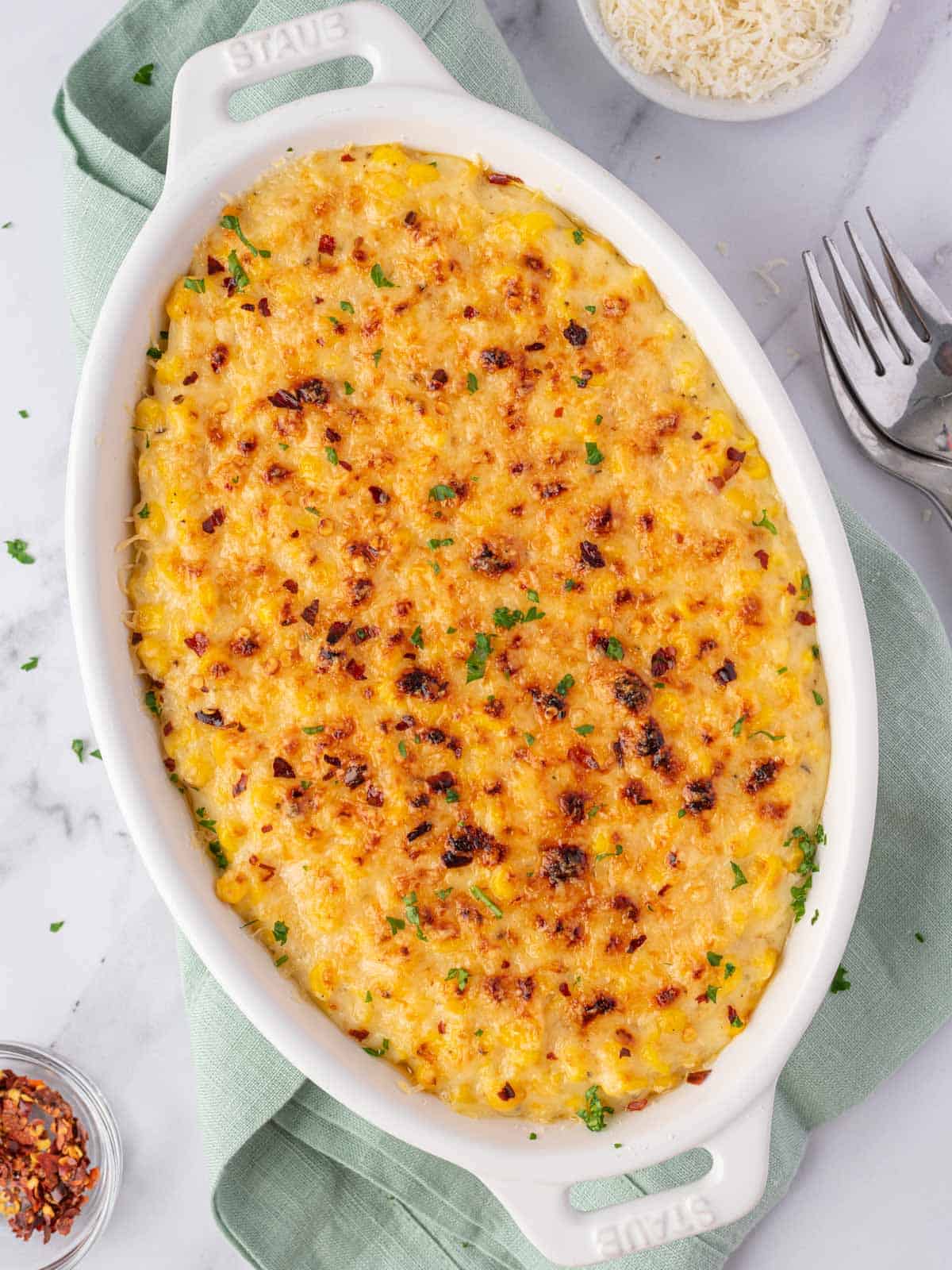 Corn casserole topped with browned Parmesan and fresh parsley.