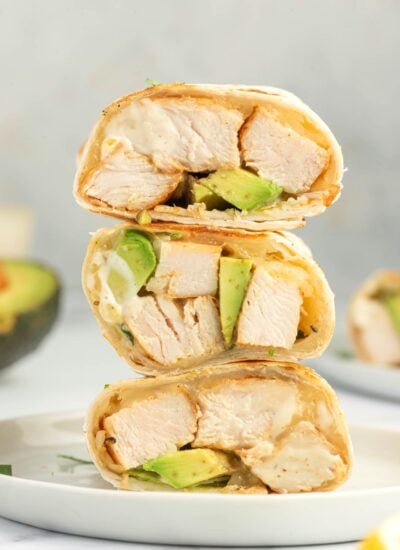 Grilled chicken, avocado and cheese in an easy chicken wrap stacked on a plate.