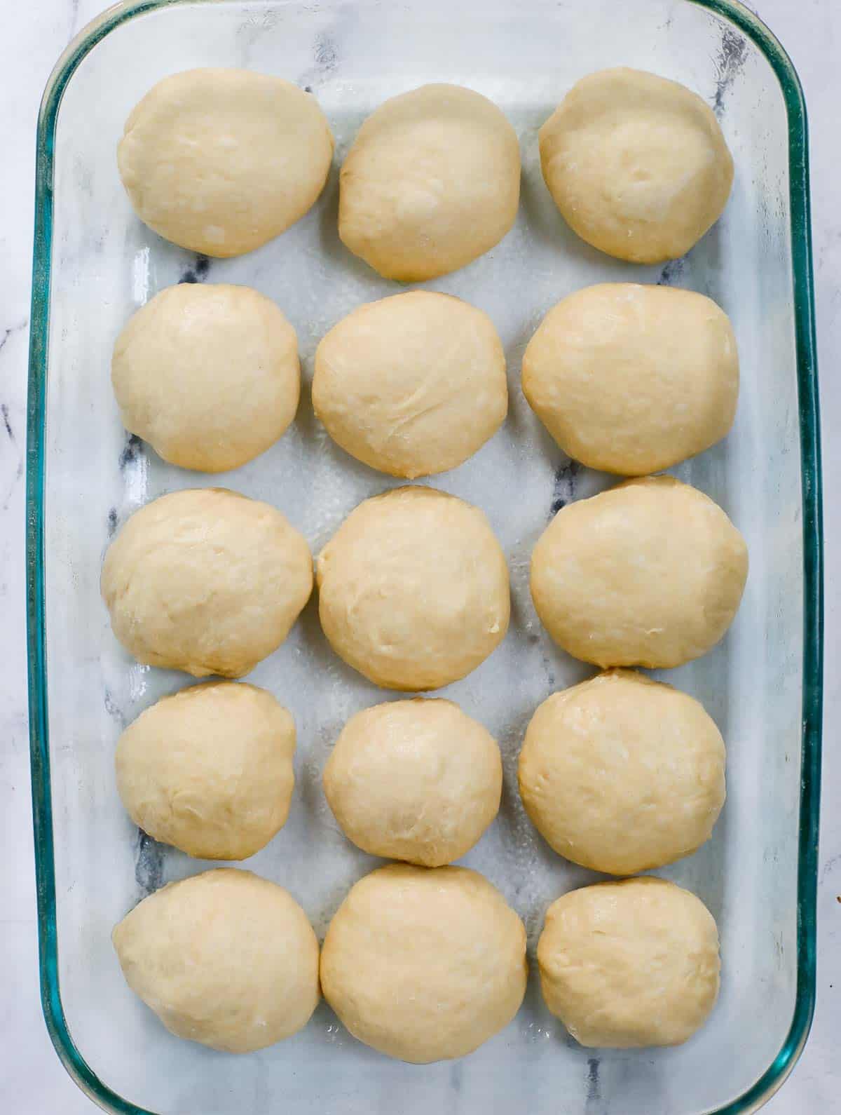 dough balls lined up in a baking dish.