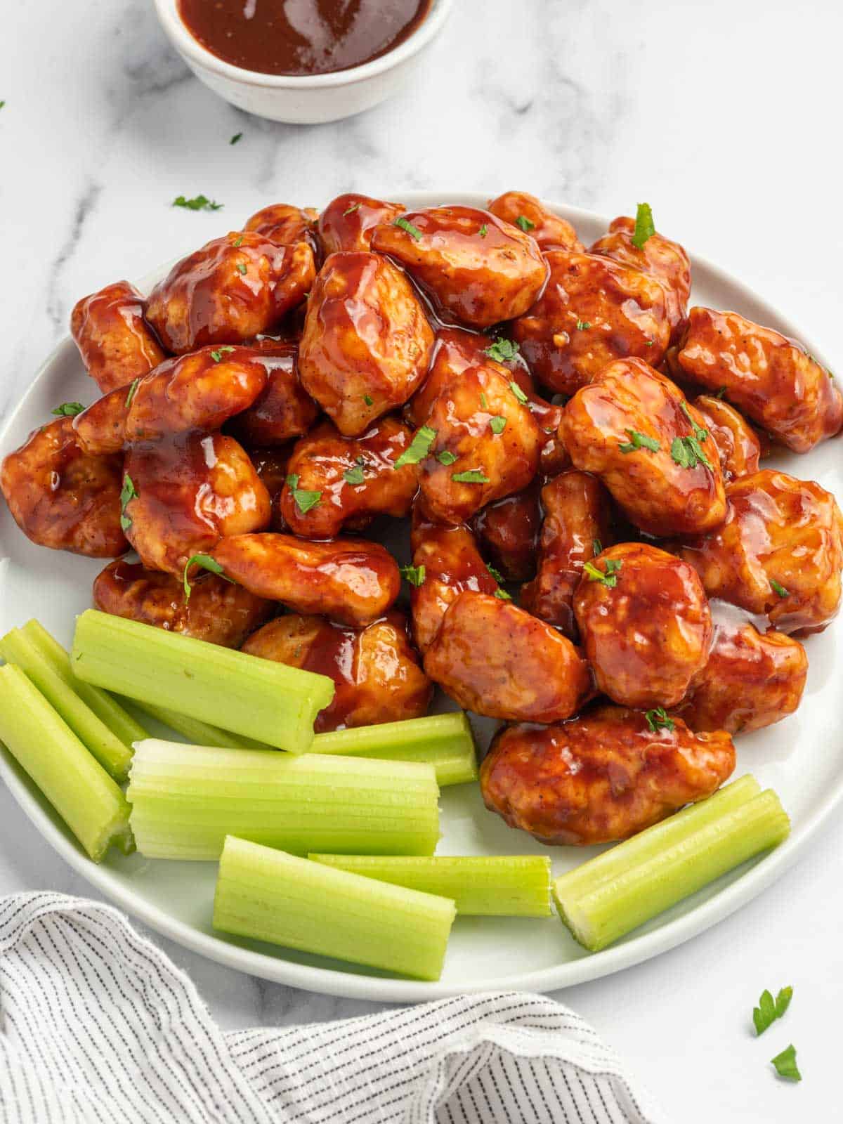 Chicken bites on a plate with celery.