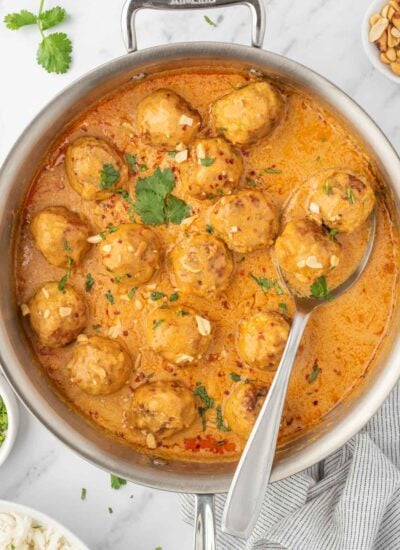 Meatballs in a skillet with coconut curry sauce.