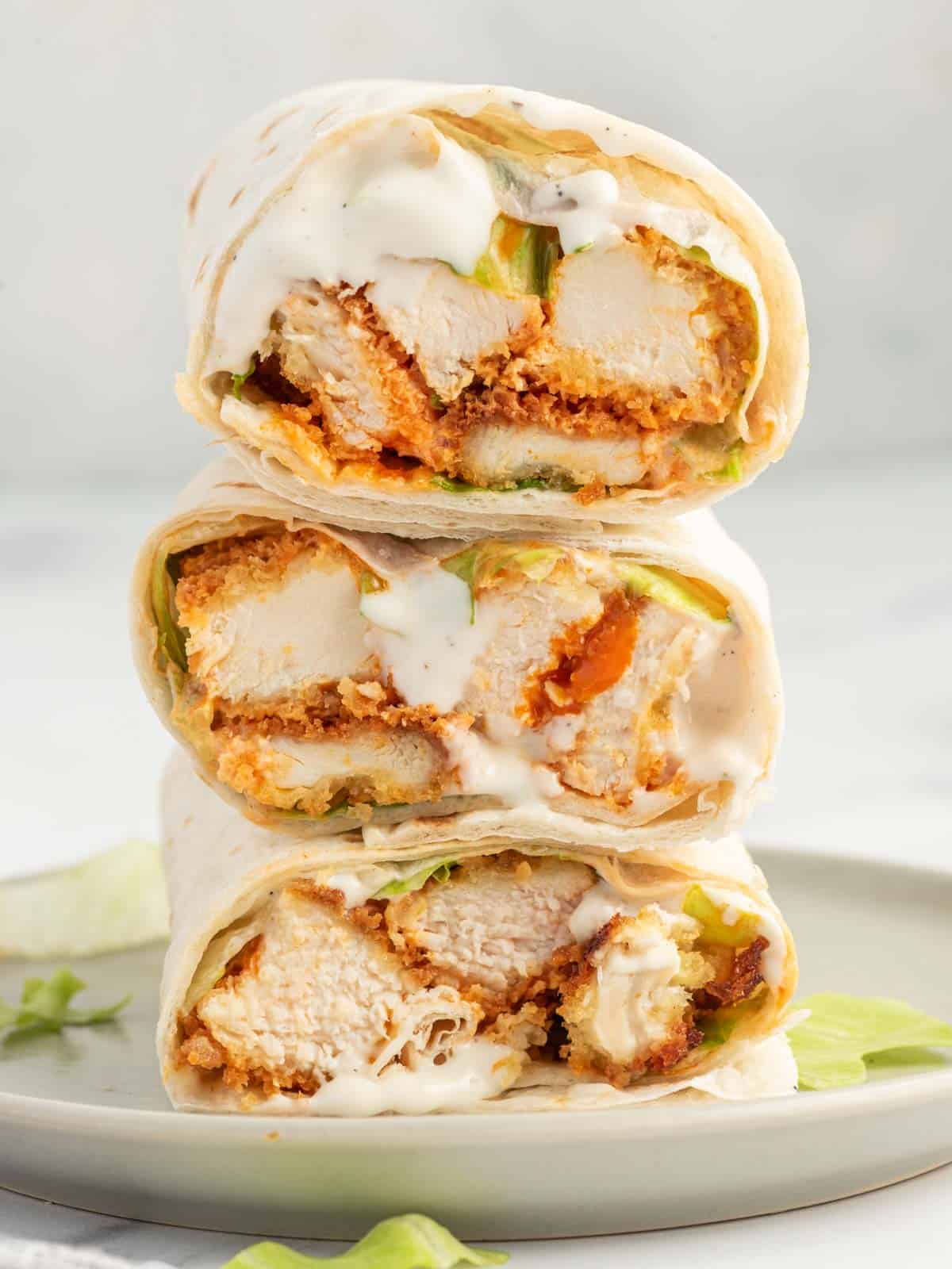 Crispy Buffalo chicken wrap sliced into pieces and stacked on a plate.