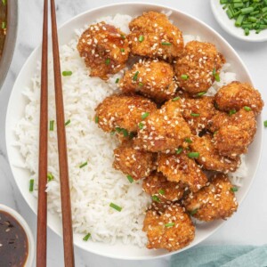 Chop sticks rest on a bowl of rice and vegan sesame cauliflower.