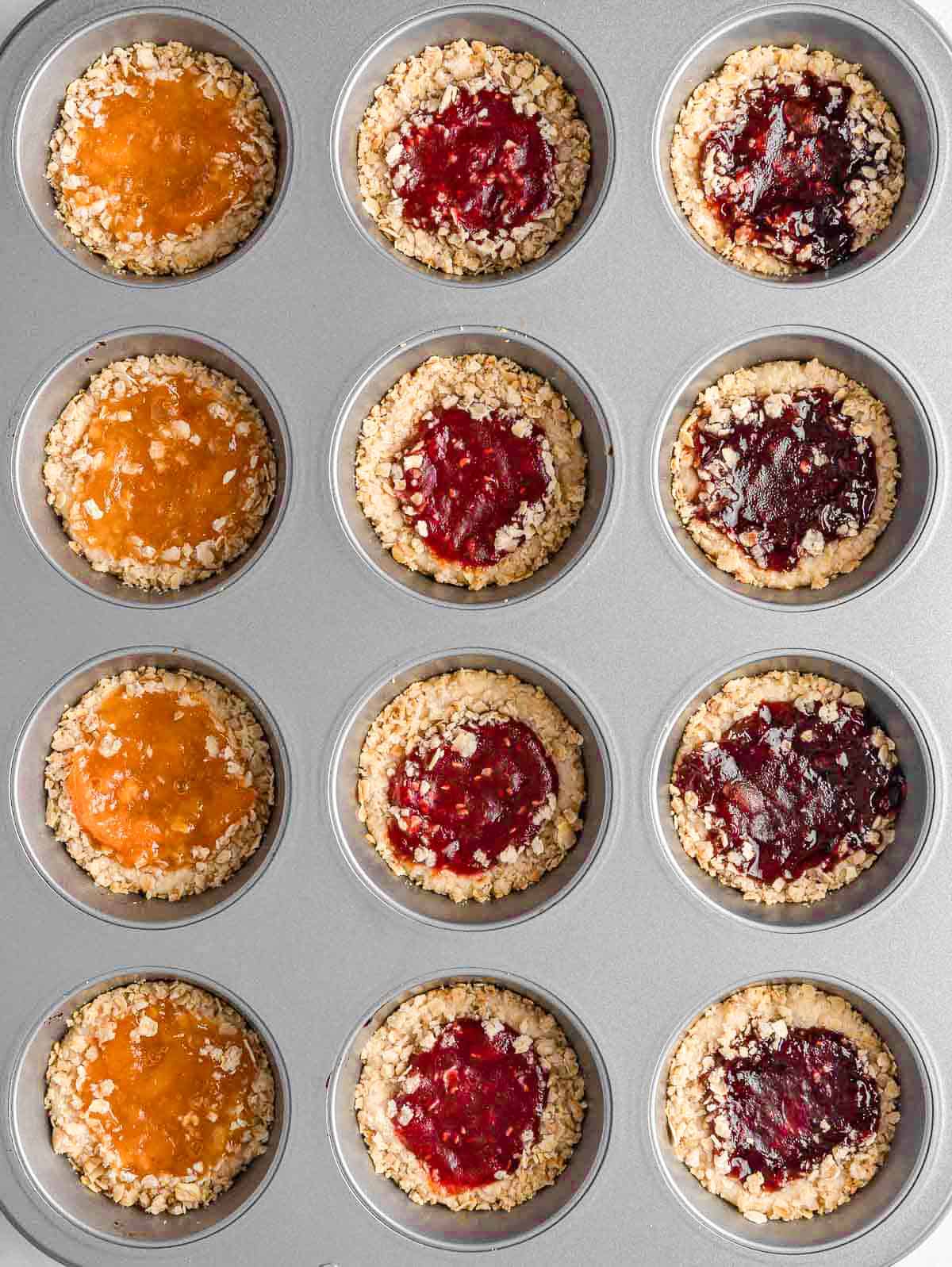Baked jam filled cookies in a muffin tin.