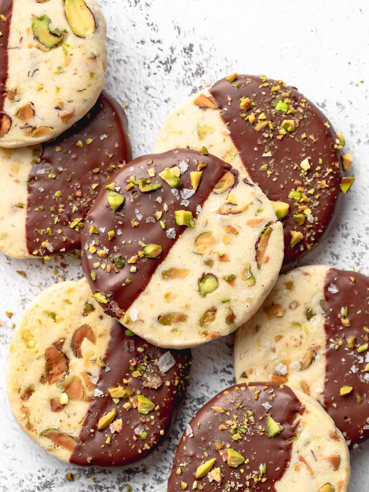 A plate of pistachio shortbread cookies dipped in chocolate.