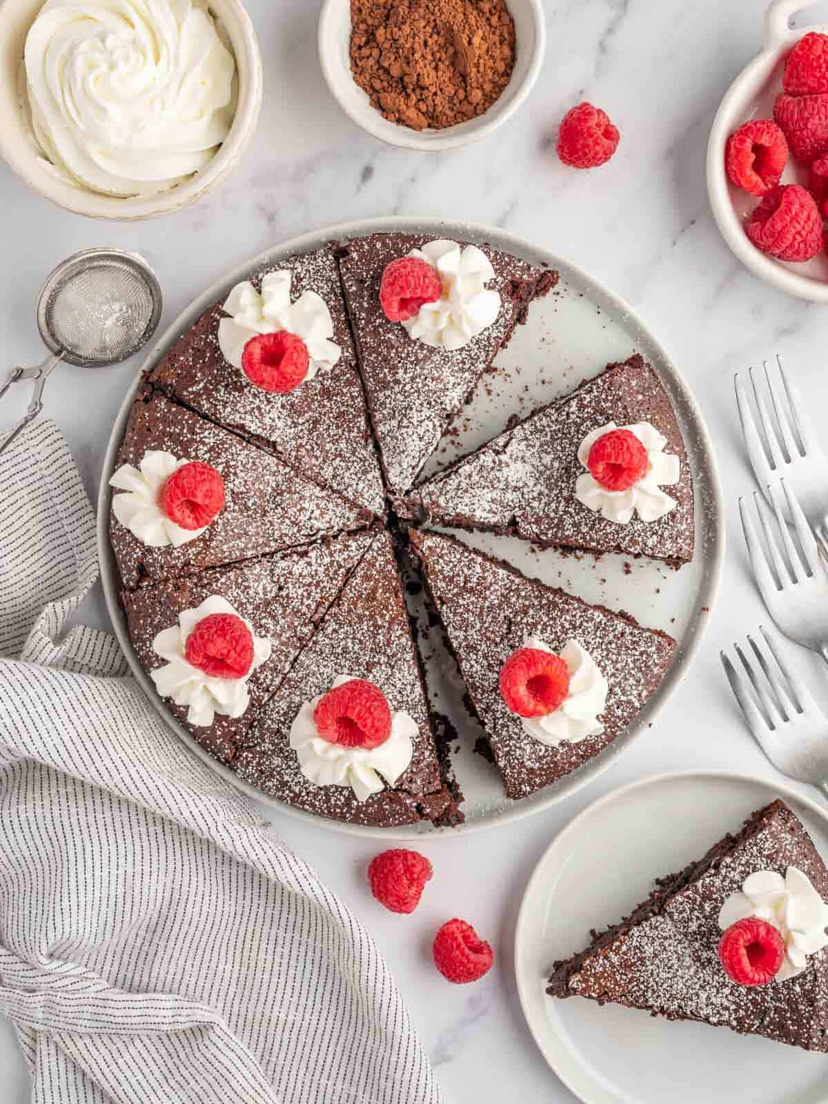 A flourless chocolate cake with a slice on a serving plate.