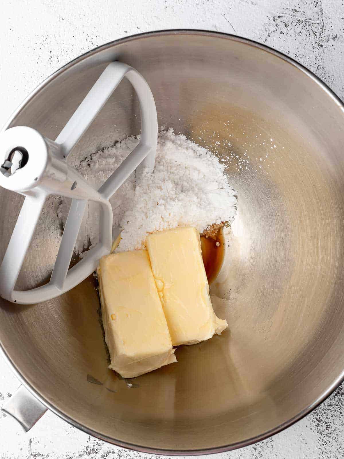 Softened butter with powdered sugar and vanilla in a stand mixer bowl.