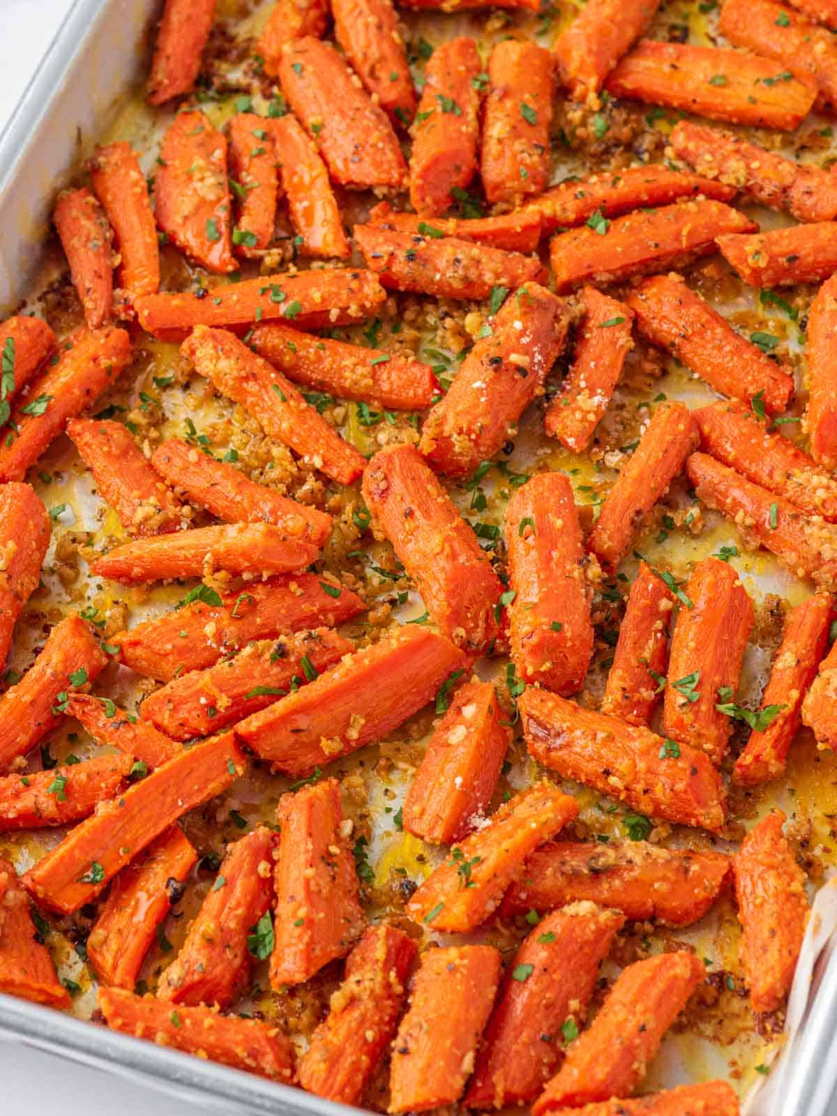 Roasted carrots with Parmesan and parsley spread across a baking sheet.