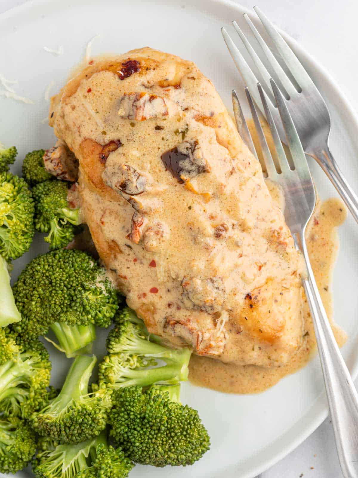 Creamy chicken recipe on a plate with broccoli and a fork.