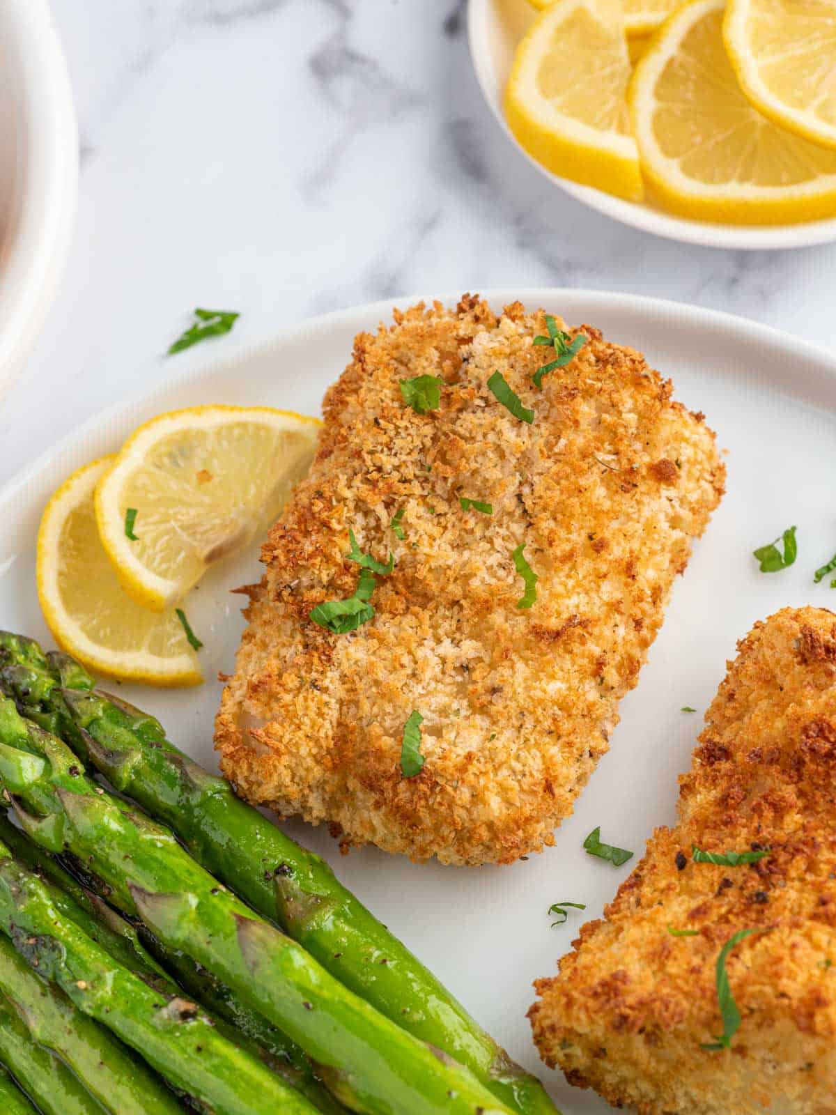 Panko crusted cod on a plate with asparagus.