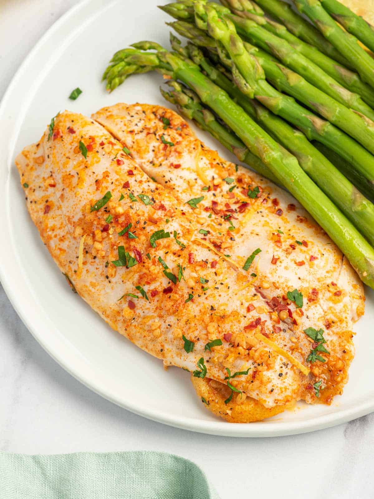 Easy baked tilapia recipe on a plate with asparagus.
