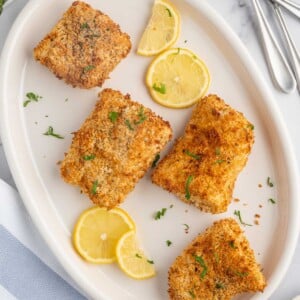 A plate of crispy air fryer cod with lemon slices.