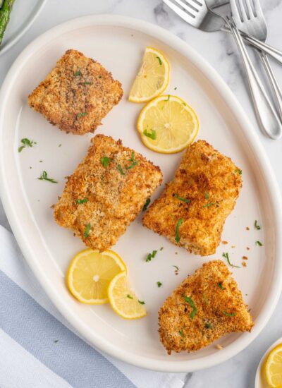 A plate of crispy air fryer cod with lemon slices.