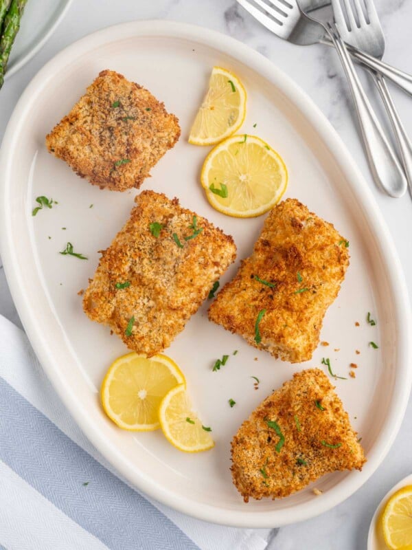 A plate of crispy air fryer cod with lemon slices.