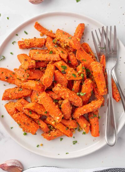 roasted carrots with parmesan cheese on a plate with two forks.