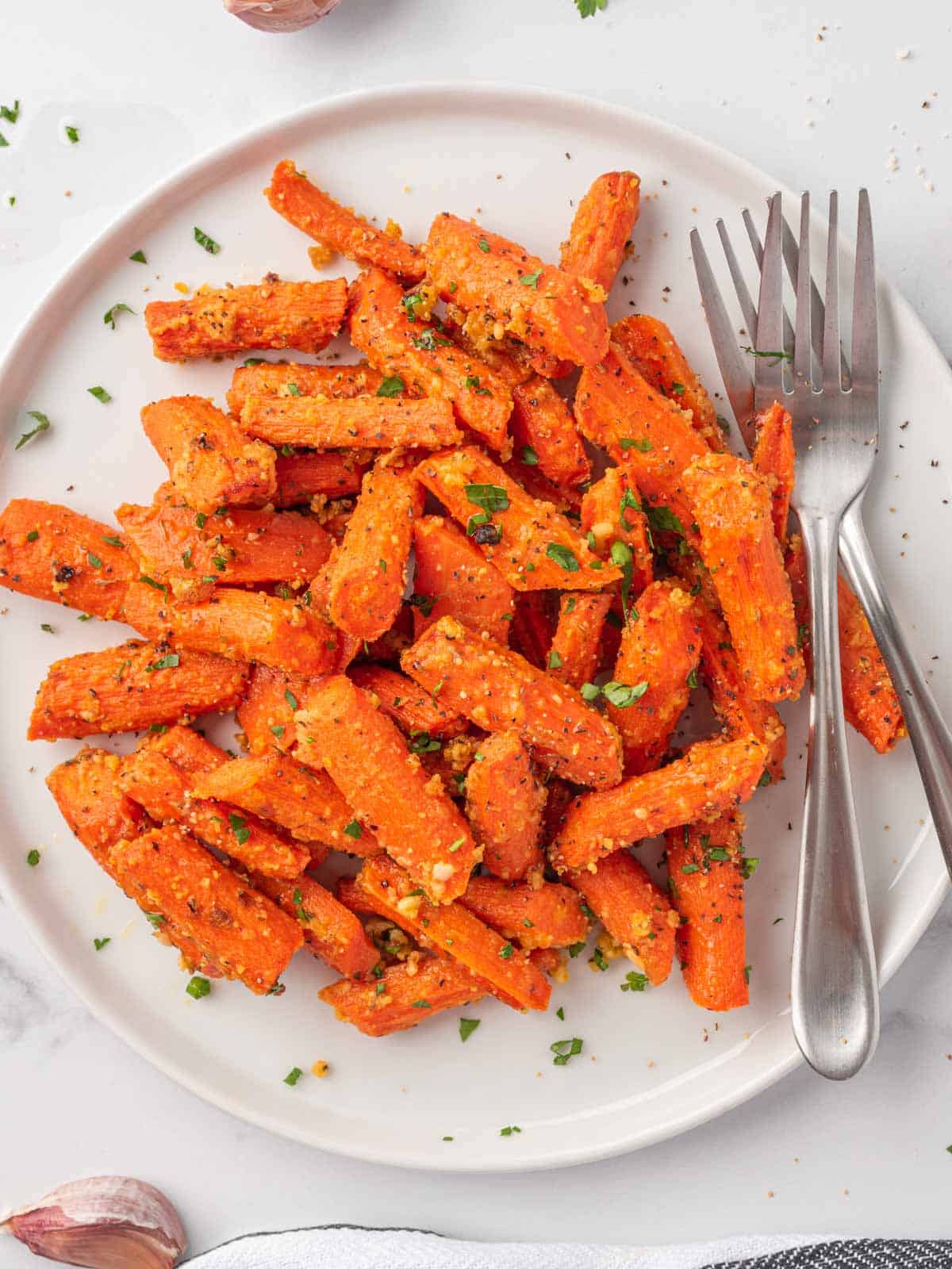 roasted carrots with parmesan cheese on a plate with two forks.