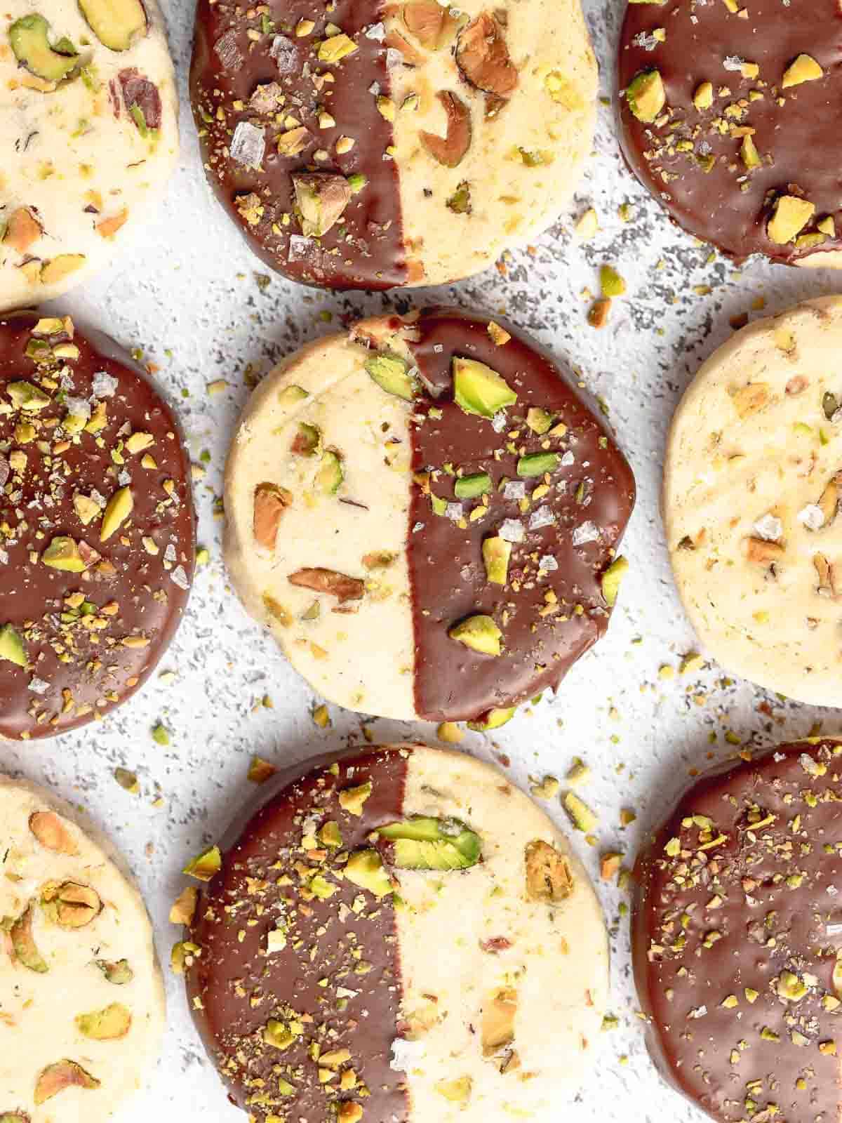 Shortbread cookies dipped in dark chocolate and topped with chopped pistachios and salt flakes.