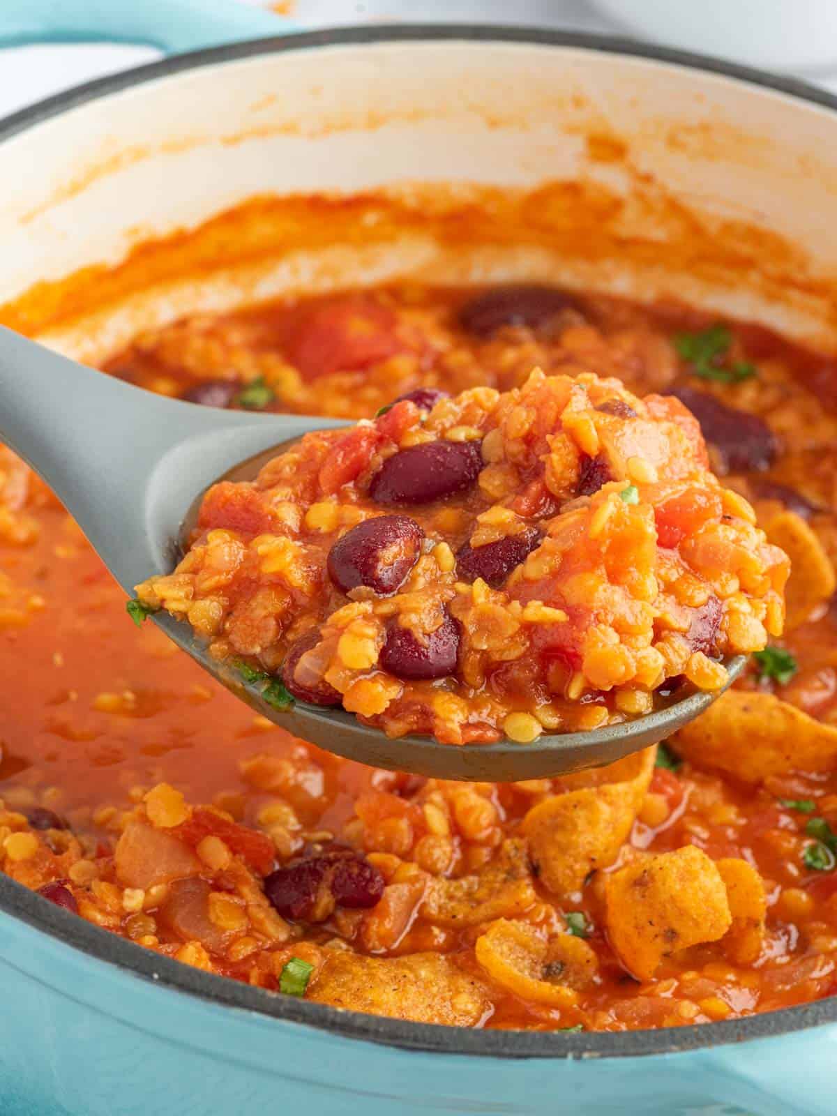 A spoon scoops a serving of meatless chili from a dutch oven.