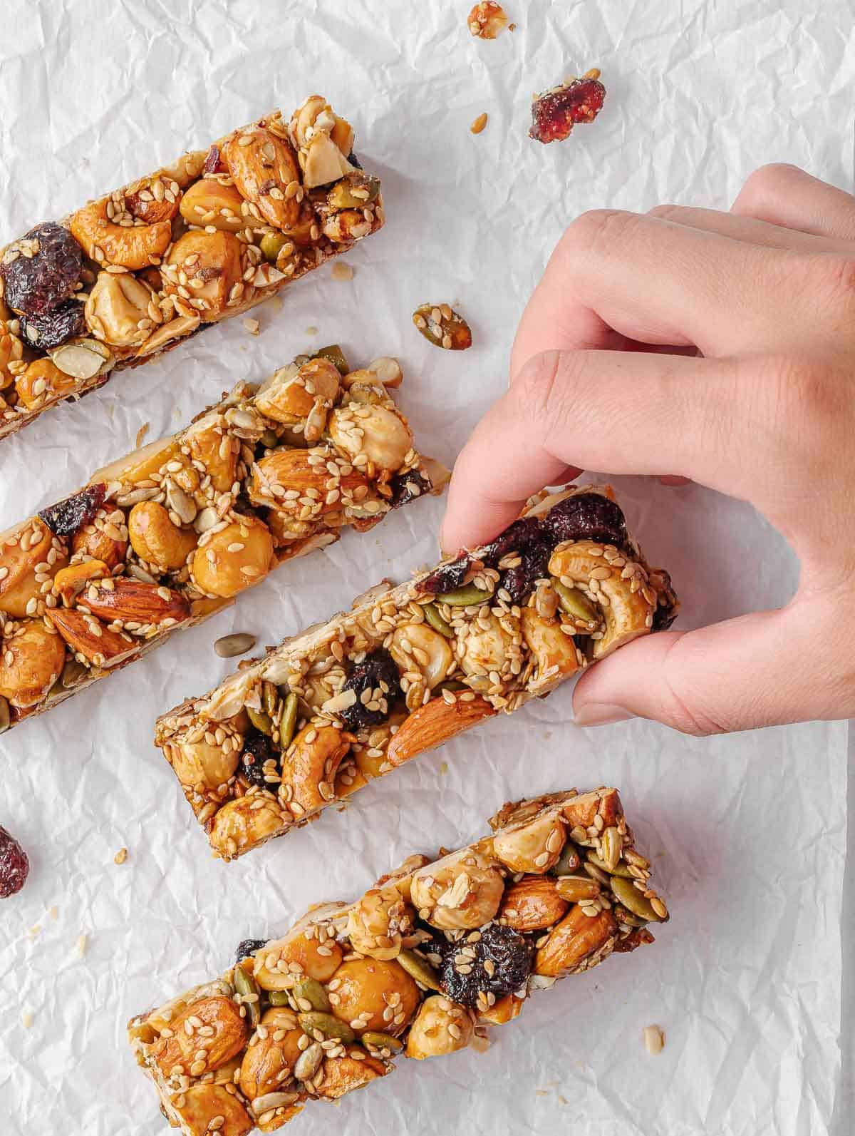 A hand picks up a seed and nut bar.