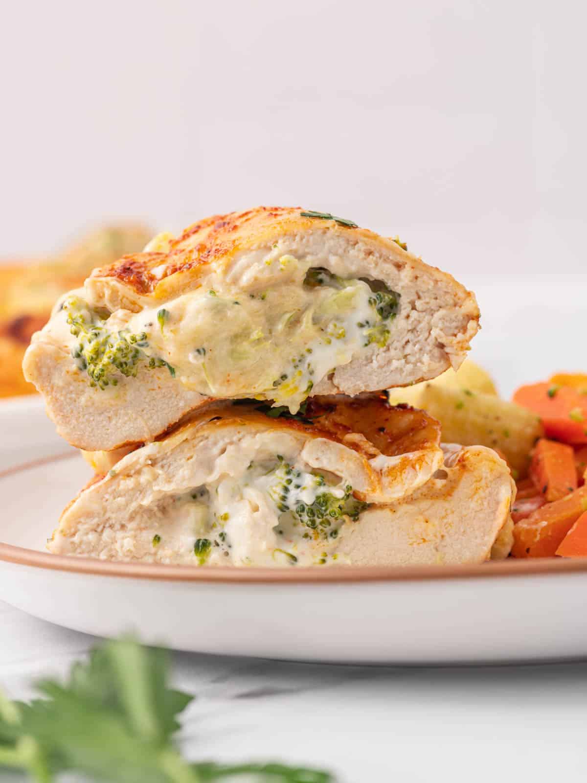 A broccoli stuffed chicken breast is cut in half on a plate.