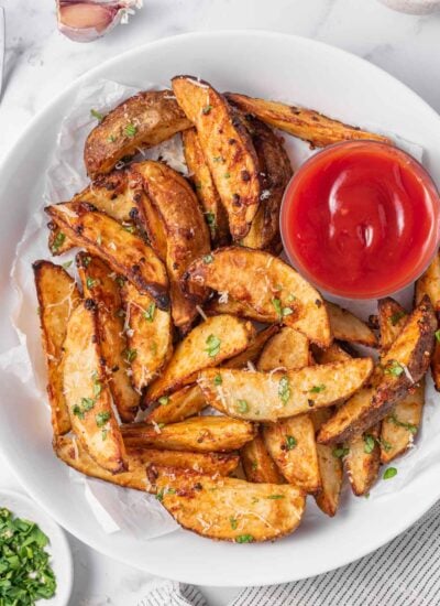 A plate of potato wedges air fryer with ketchup for dipping.