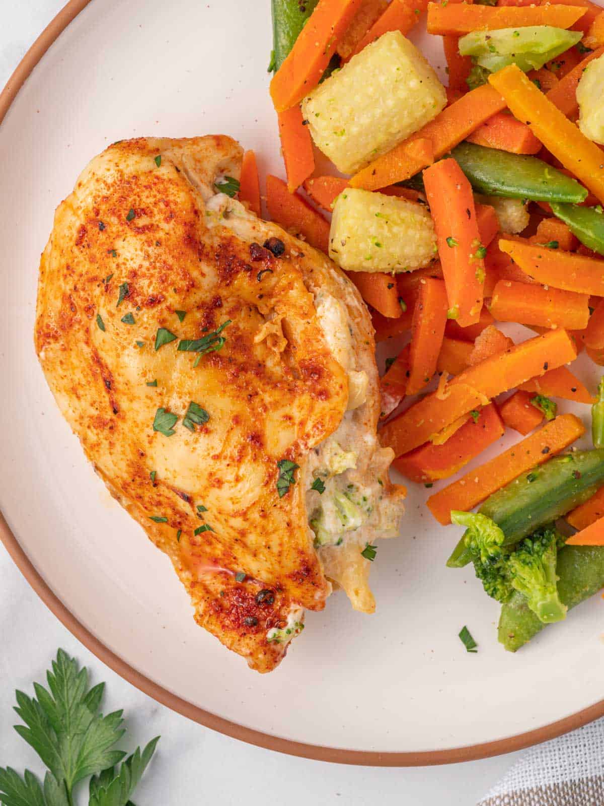 Air Fryer Broccoli stuffed chicken on a plate with veggies.
