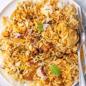 2 forks rest on a a plate of homemade chicken biryani.en