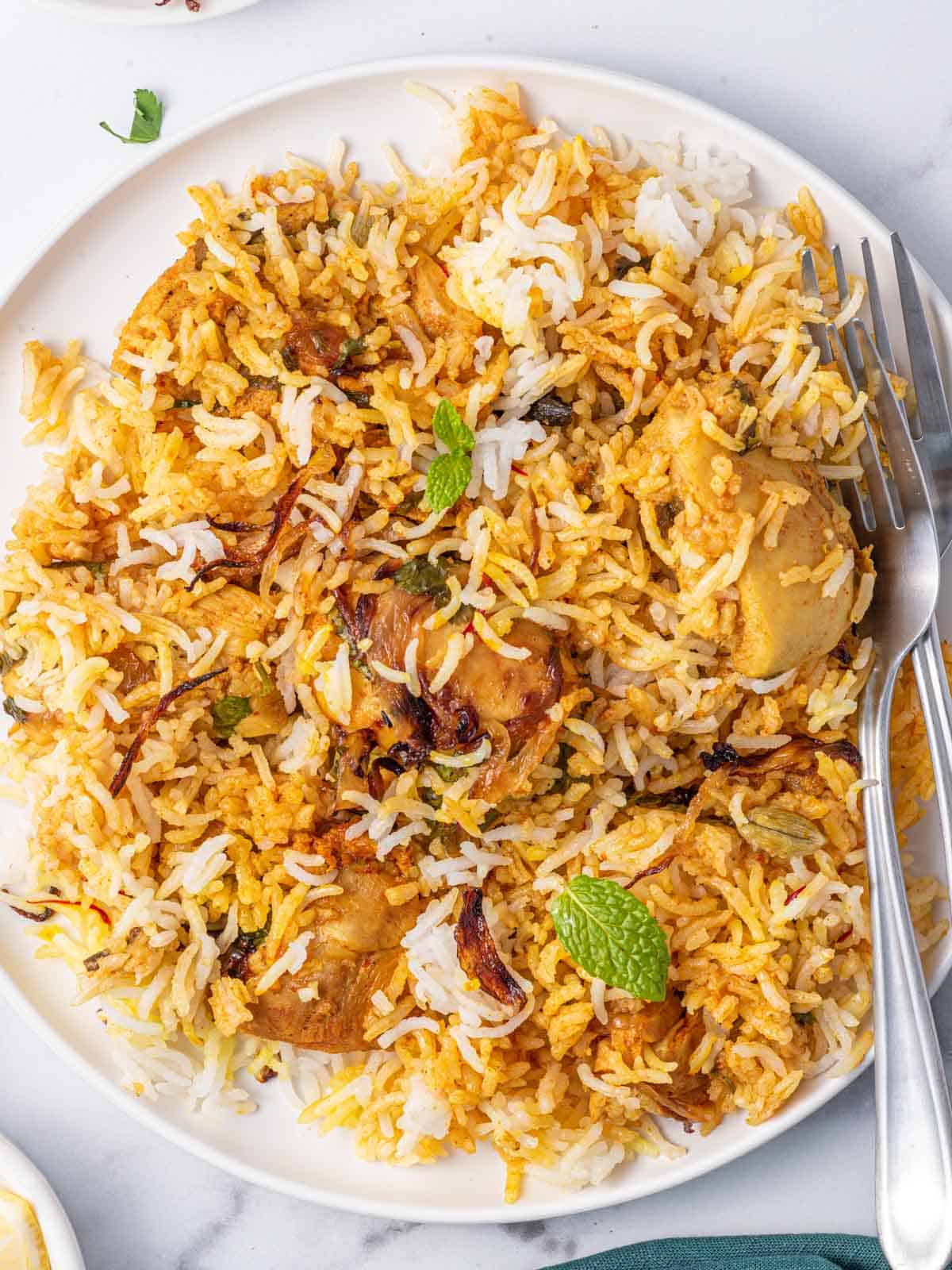 2 forks rest on a a plate of homemade chicken biryani.en