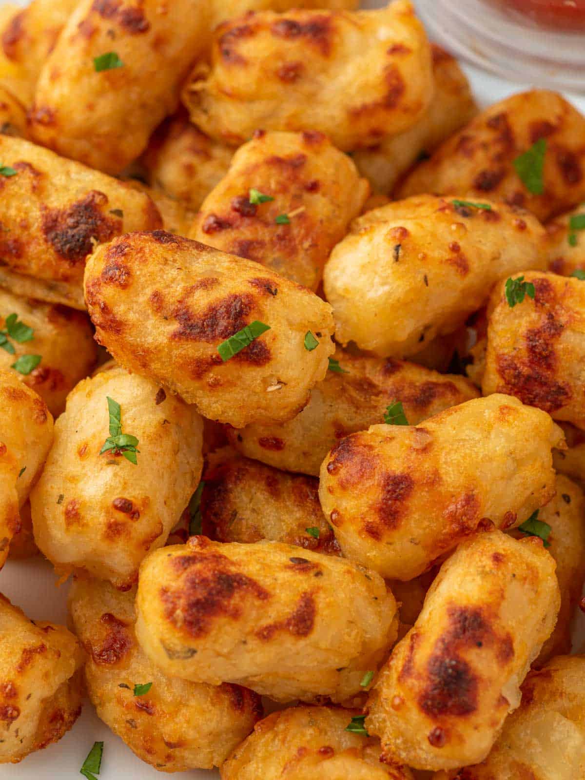 Close up of cheesy tater tots in a pile.