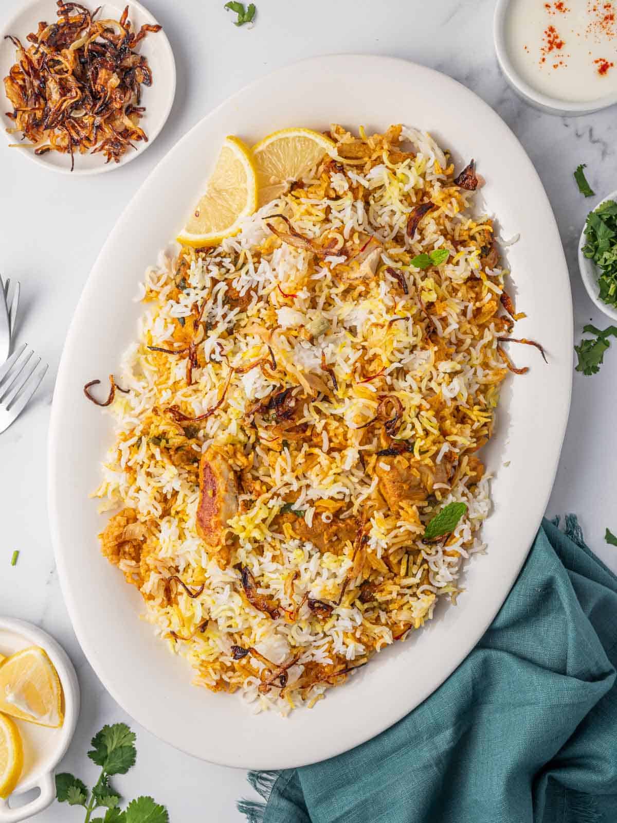 A platter of easy chicken biryani with lemon wedges.